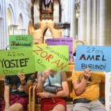 Sur la rangée de droite, les militants et sympathisants tenaient chacun des pancartes colorées avec le nom, l'âge et le pays d'origine de requérants d'asile déboutés et menacés de renvoi.